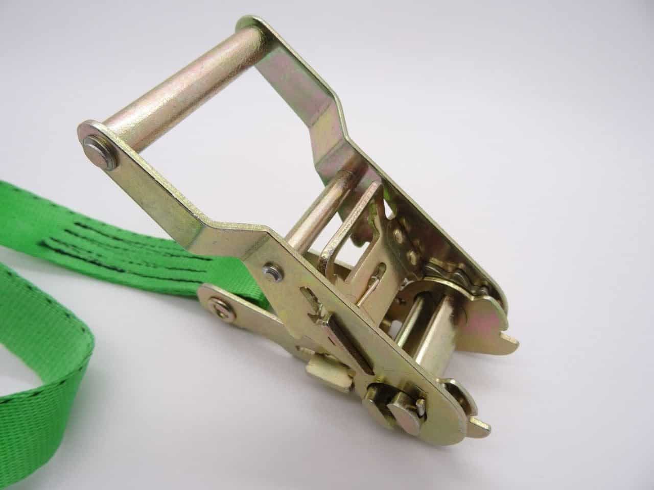 Close up of metal ratchet strap tie downs with green webbing for securing cargo