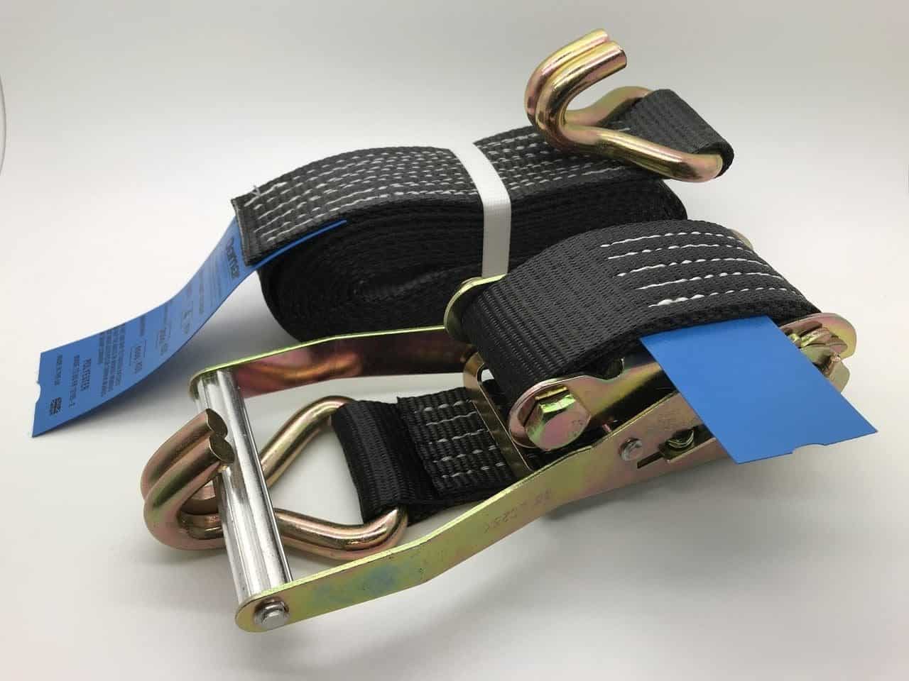 Heavy-duty ratchet straps tie down with black webbing and metal hooks for secure load fastening