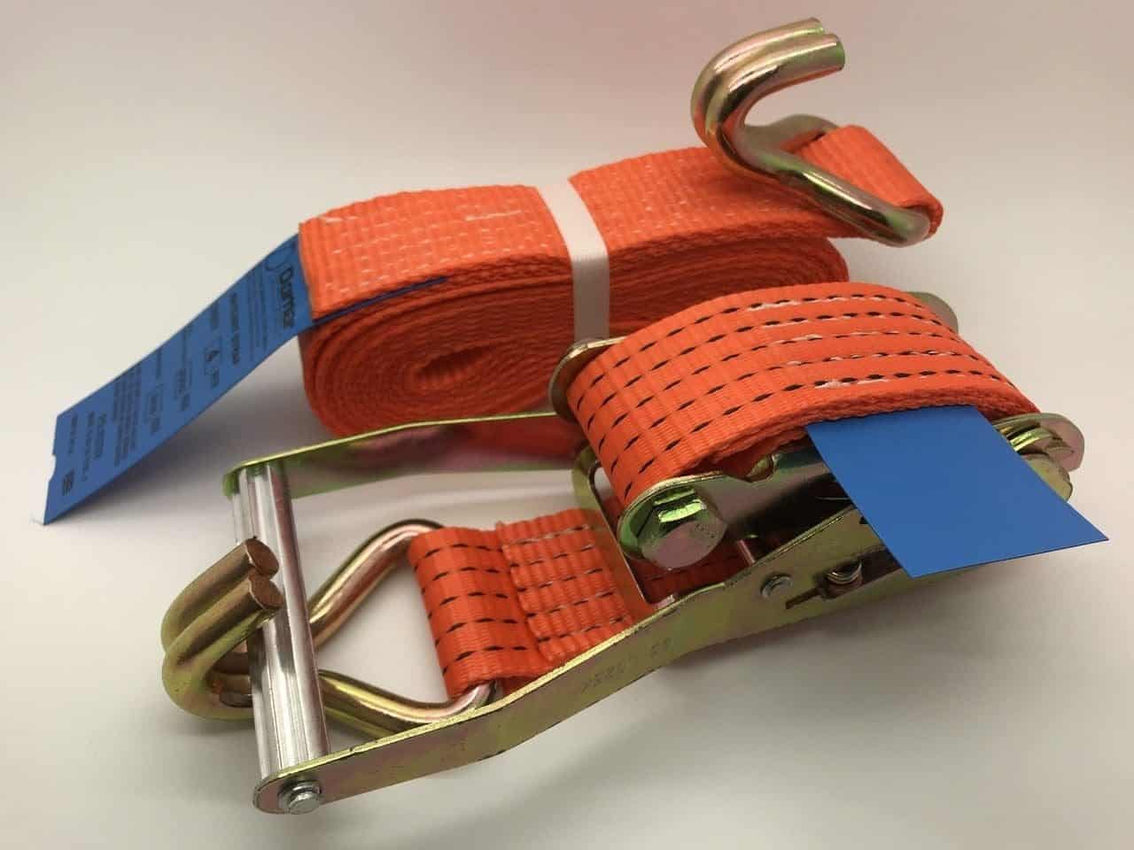 Orange ratchet straps tie down with metal hooks and ratchet mechanism for secure cargo fastening